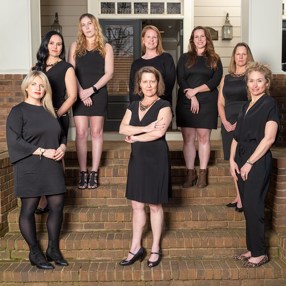 The Pain Care Labs team stands staggered on stairsteps looking into camera.